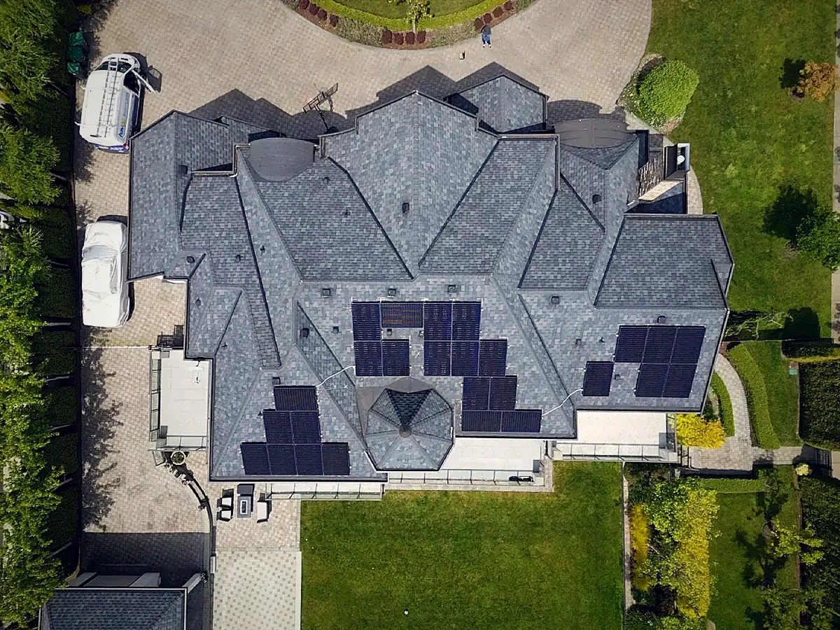 Overhead view of solar panel arrays on the pitched roof of a large house