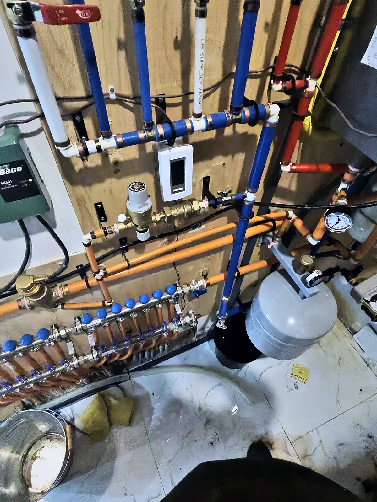 Hydronic heating piping with a radiant floor manifold, expansion tank, gauges and zone controls