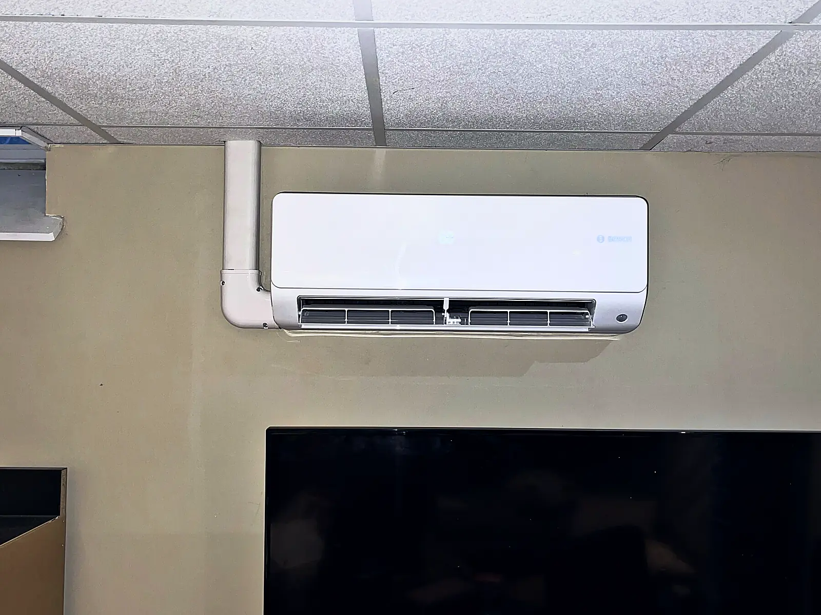 Wall-mounted ductless indoor unit with a covered line set in an office