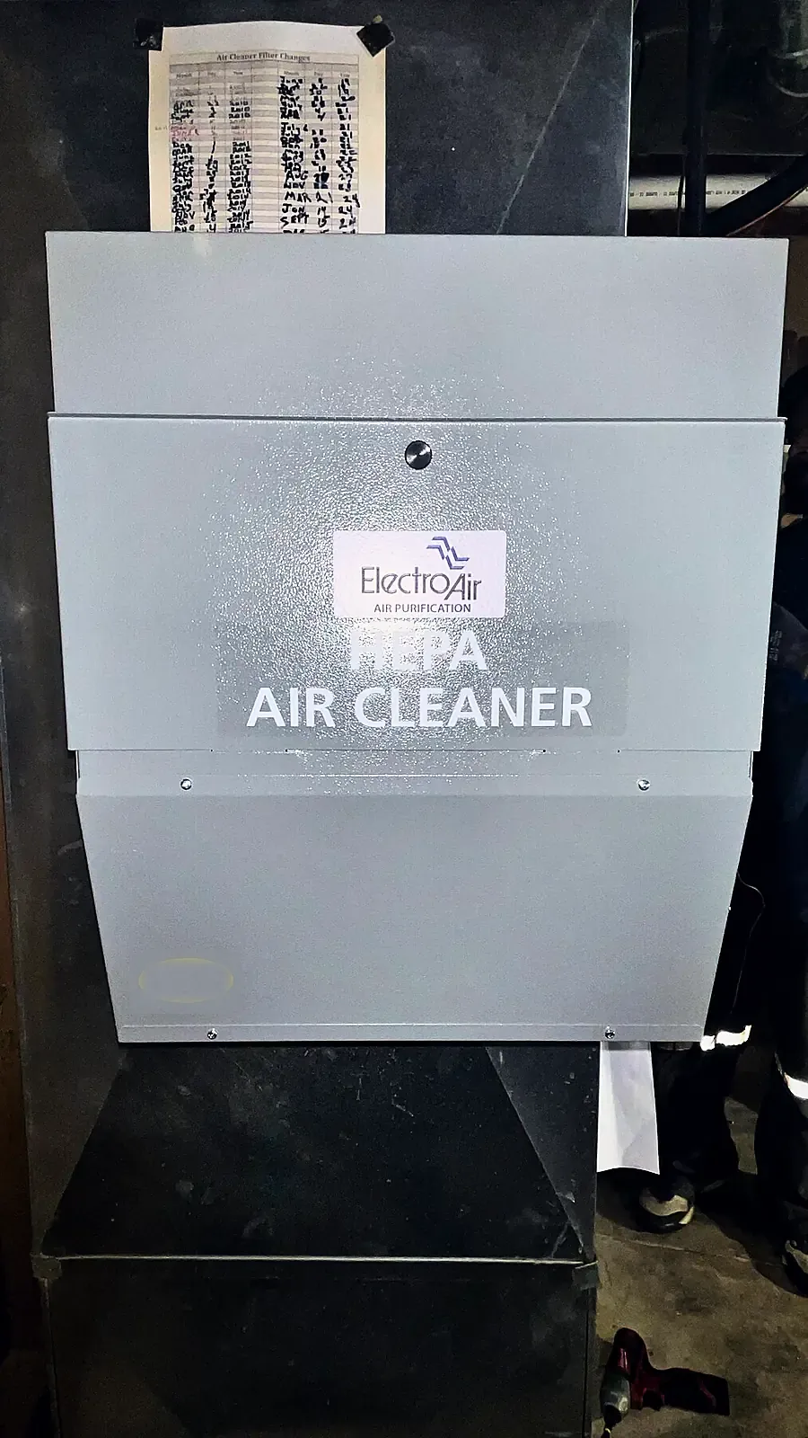 Grey ducted HEPA air cleaner cabinet with its filter change log