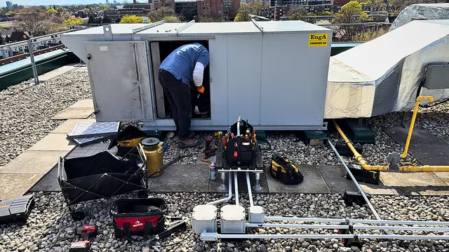 Technician servicing a rooftop unit with panels open